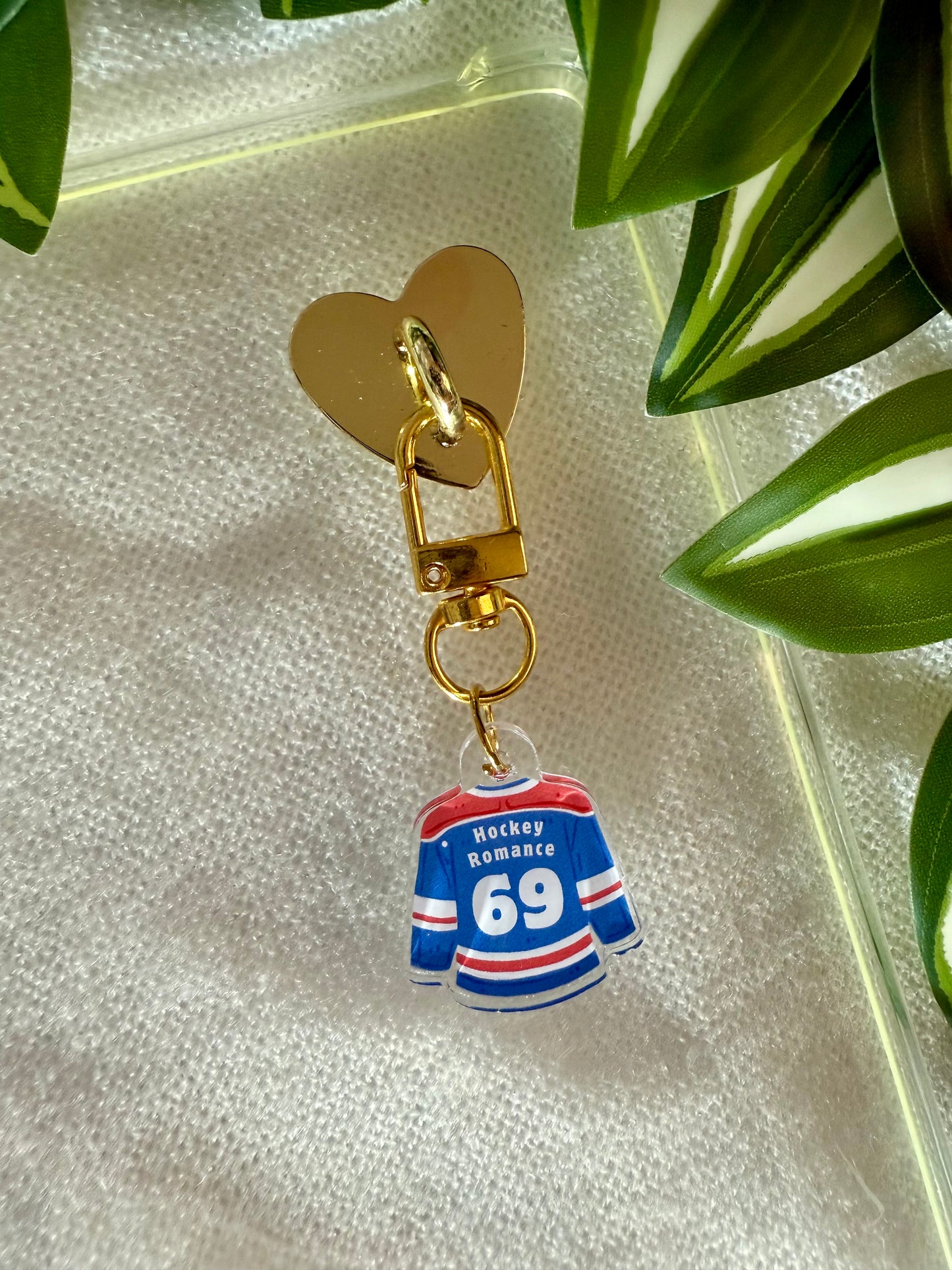 Keychain with hockey jersey charm on a reflective surface with green leaves in the background
