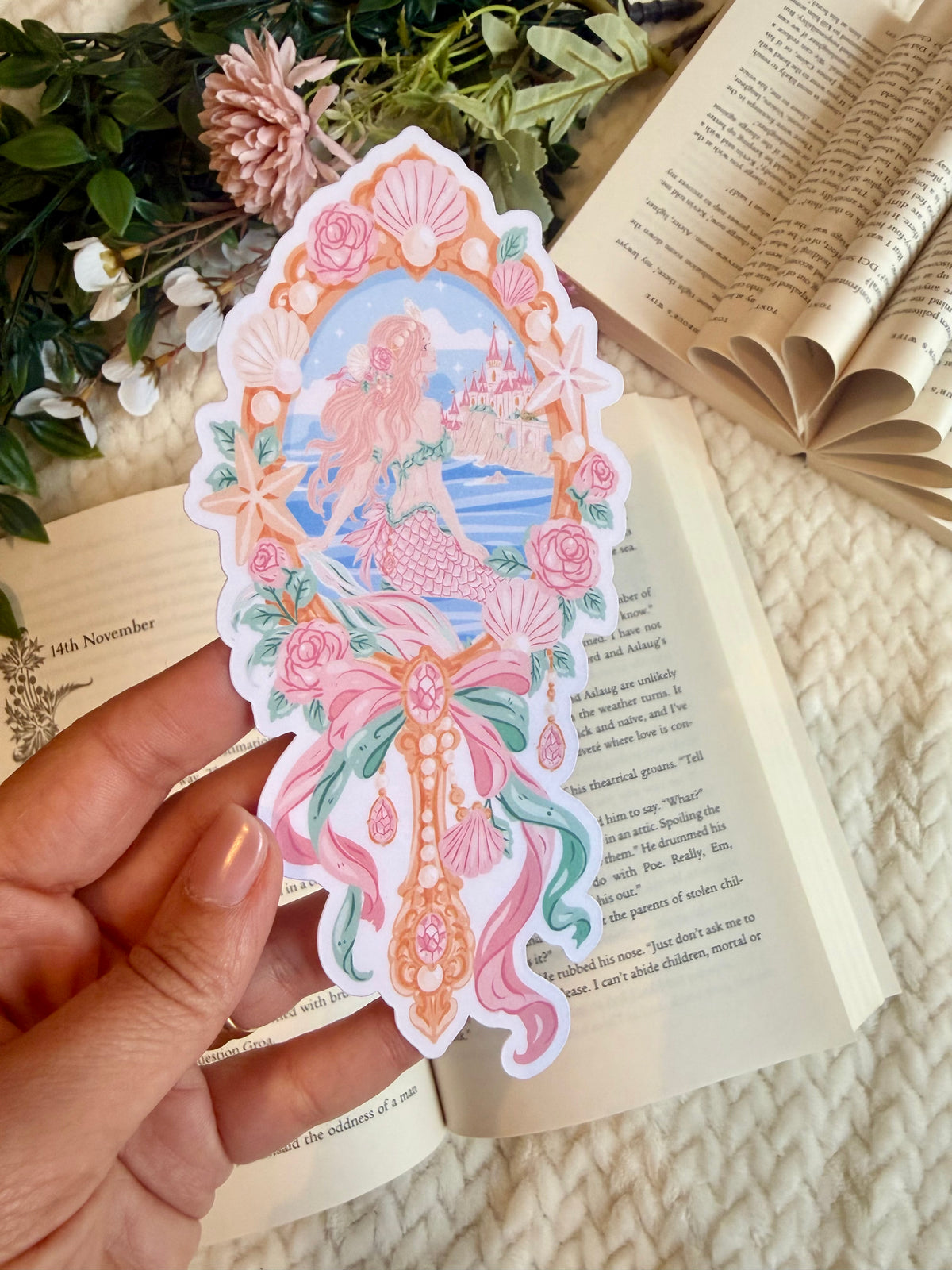 A die cut bookmark of an enchanted mirror with the image of a mermaid and castle 