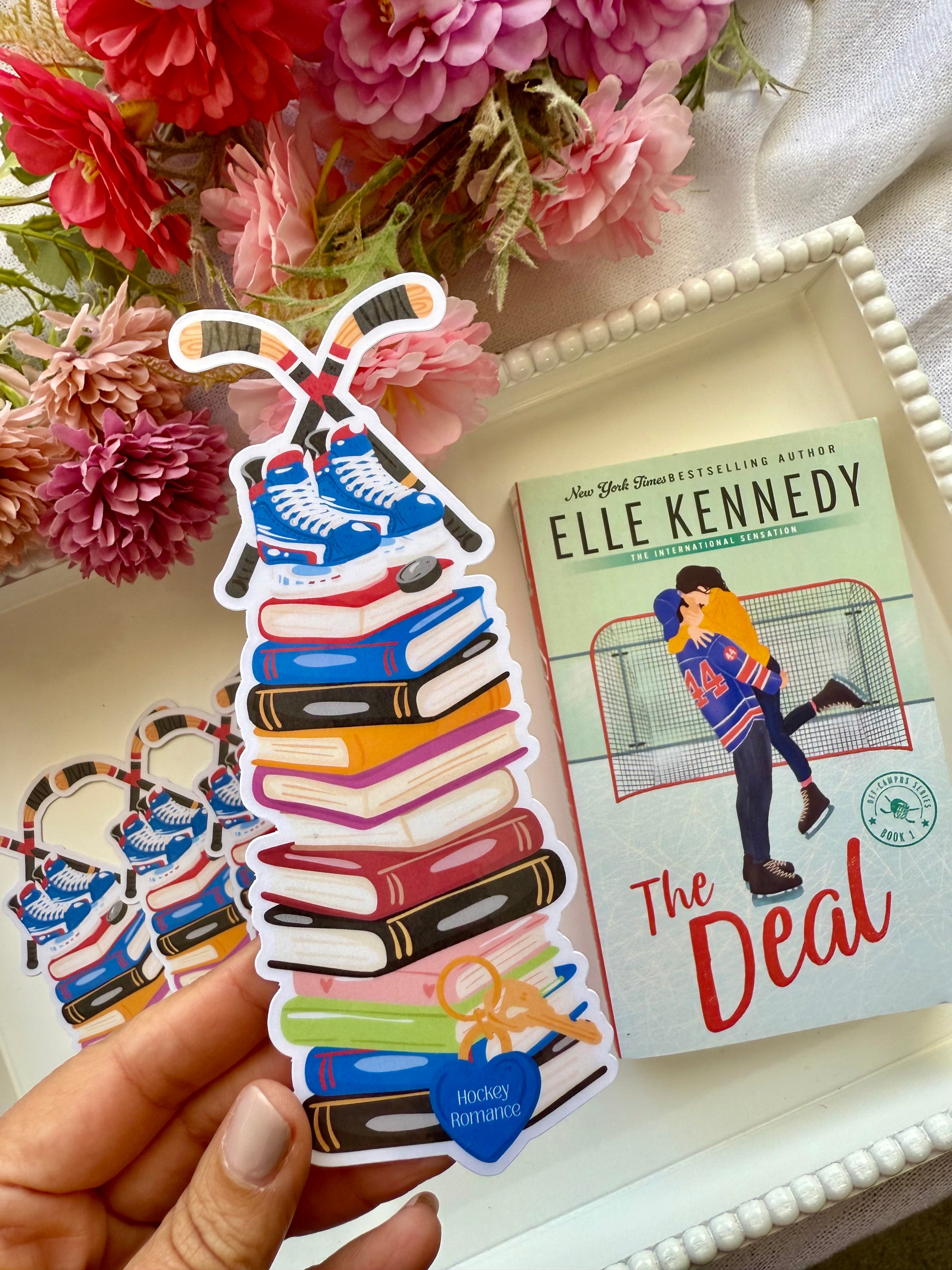 A die cut bookmark of a bookstack with hockey skates and sticks.