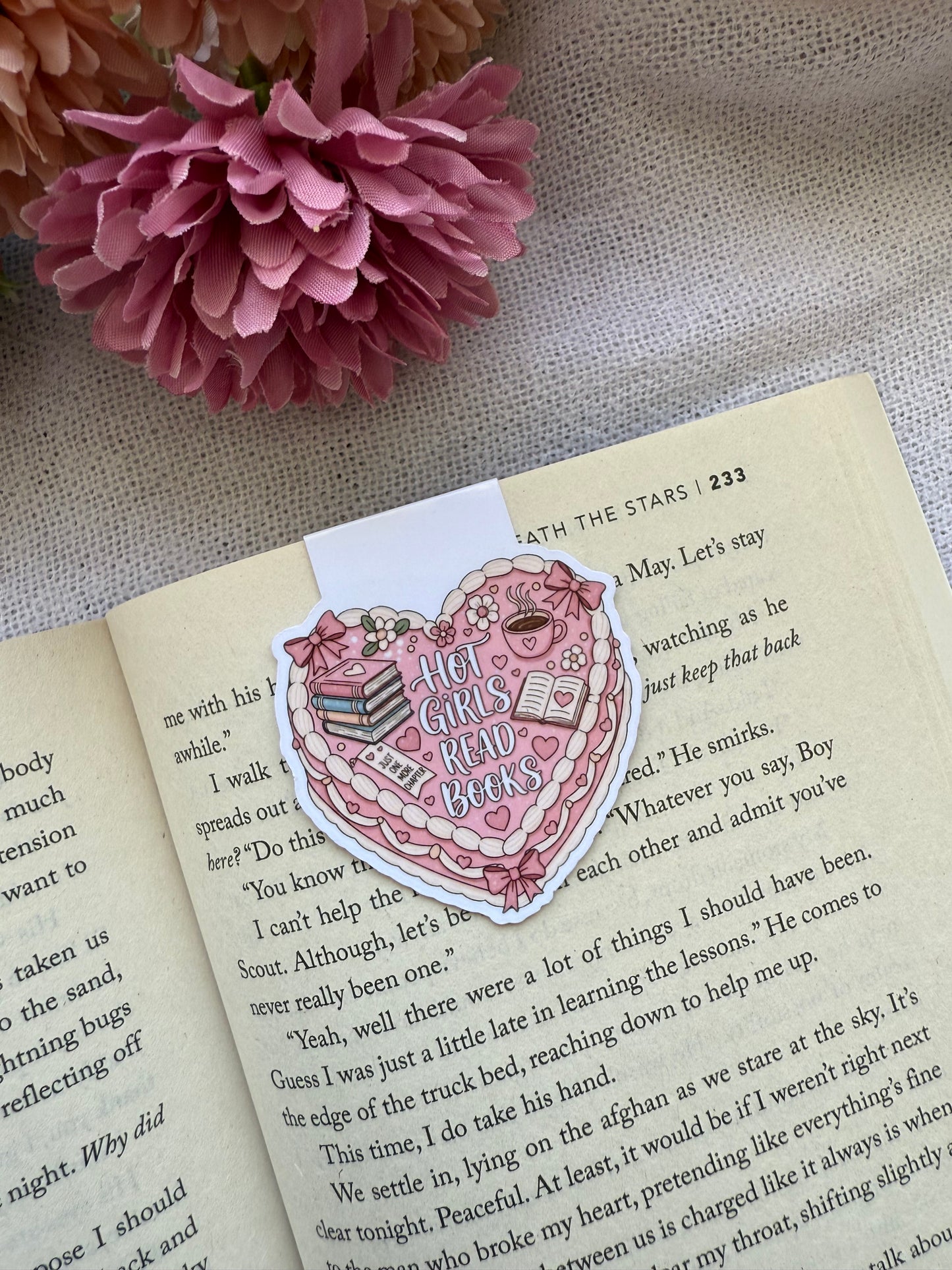 Heart-shaped coquette cake magnetic bookmark on an open book with pink flowers