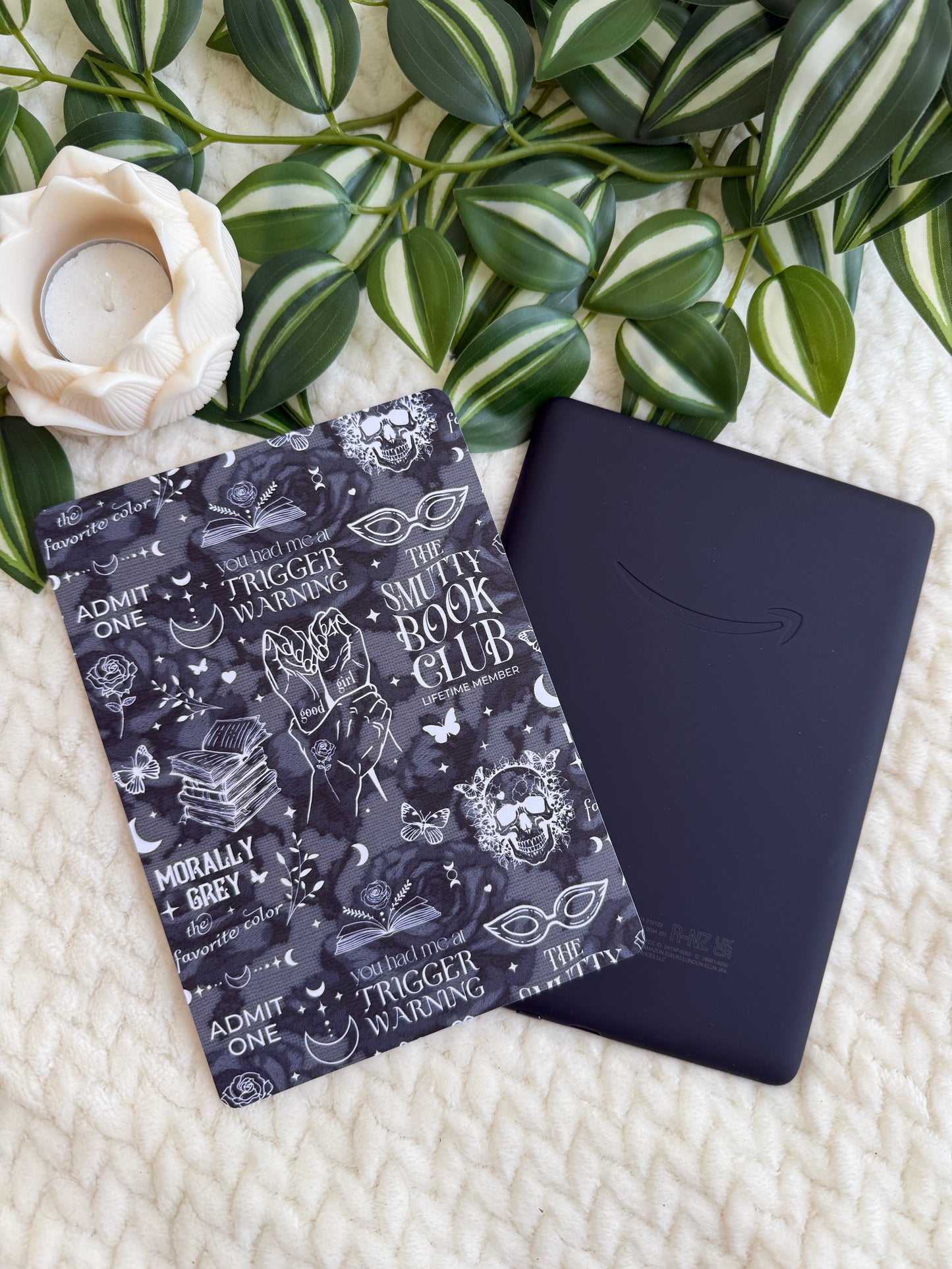 A kindle insert of with text trigger warnings and smutty book club resting on a kindle
