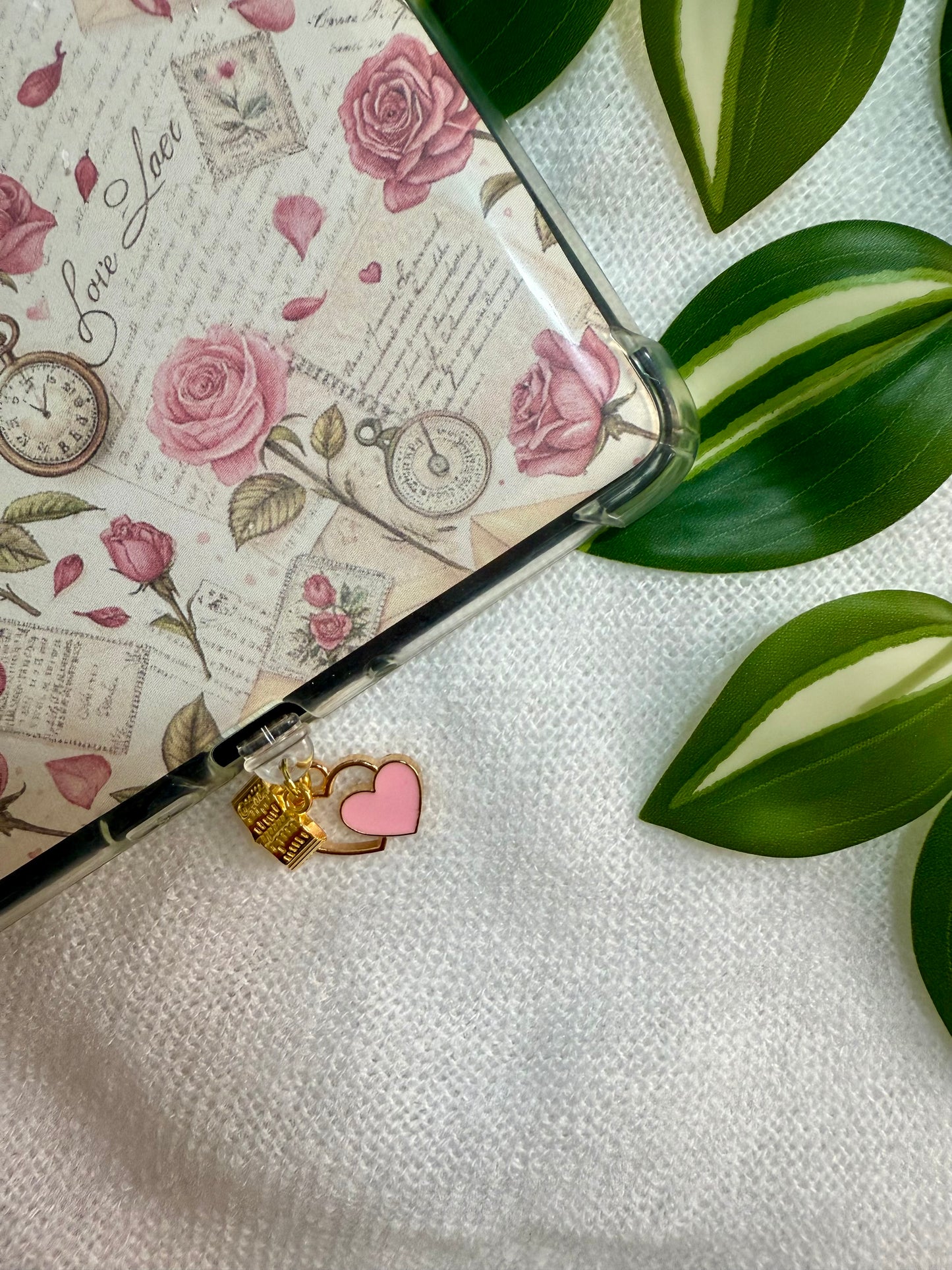 A dust plug of a heart and book attached to a floral kindle case.