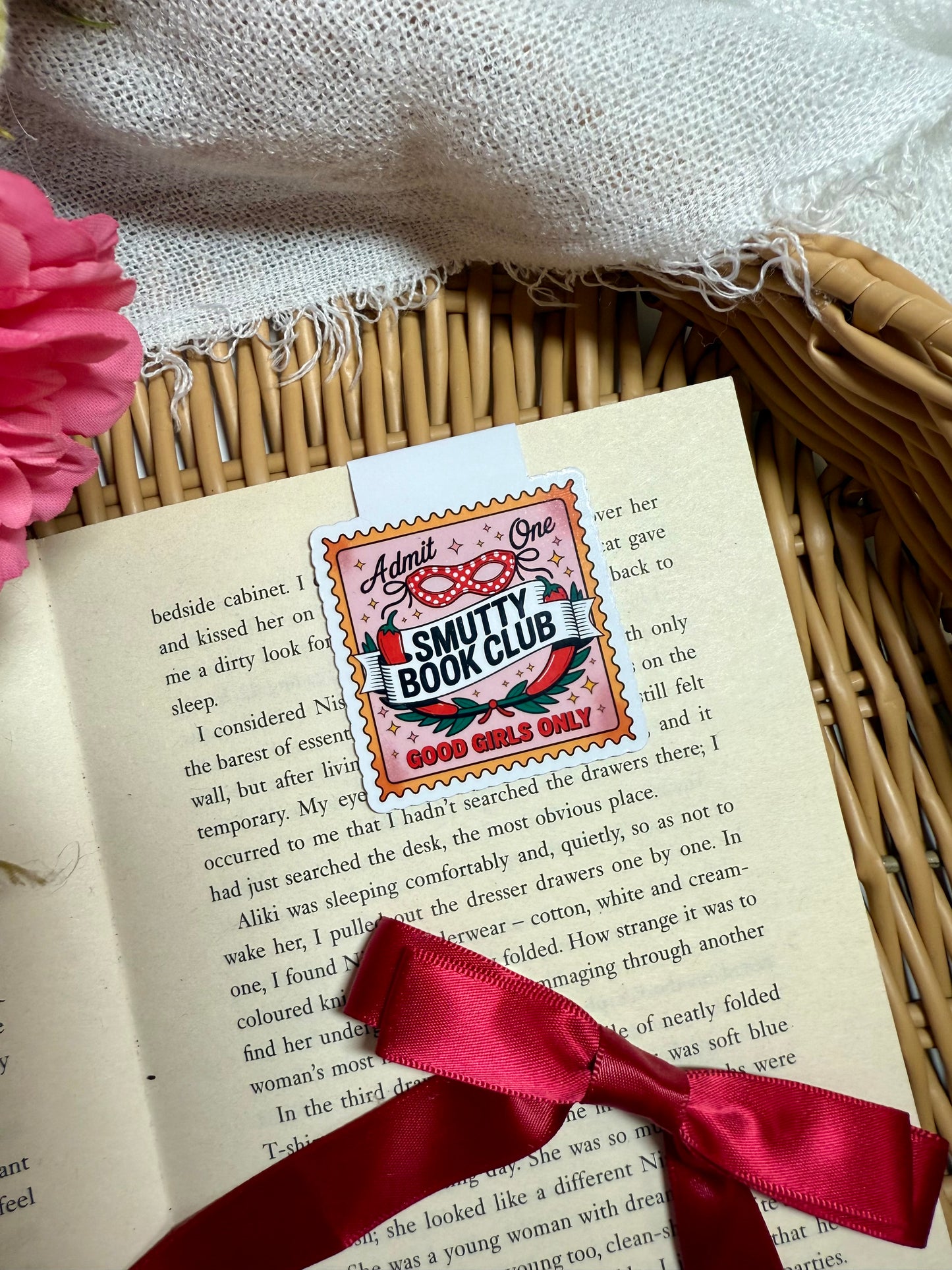 Smutty Book Club ticket magnetic bookmark on an open book with a red ribbon