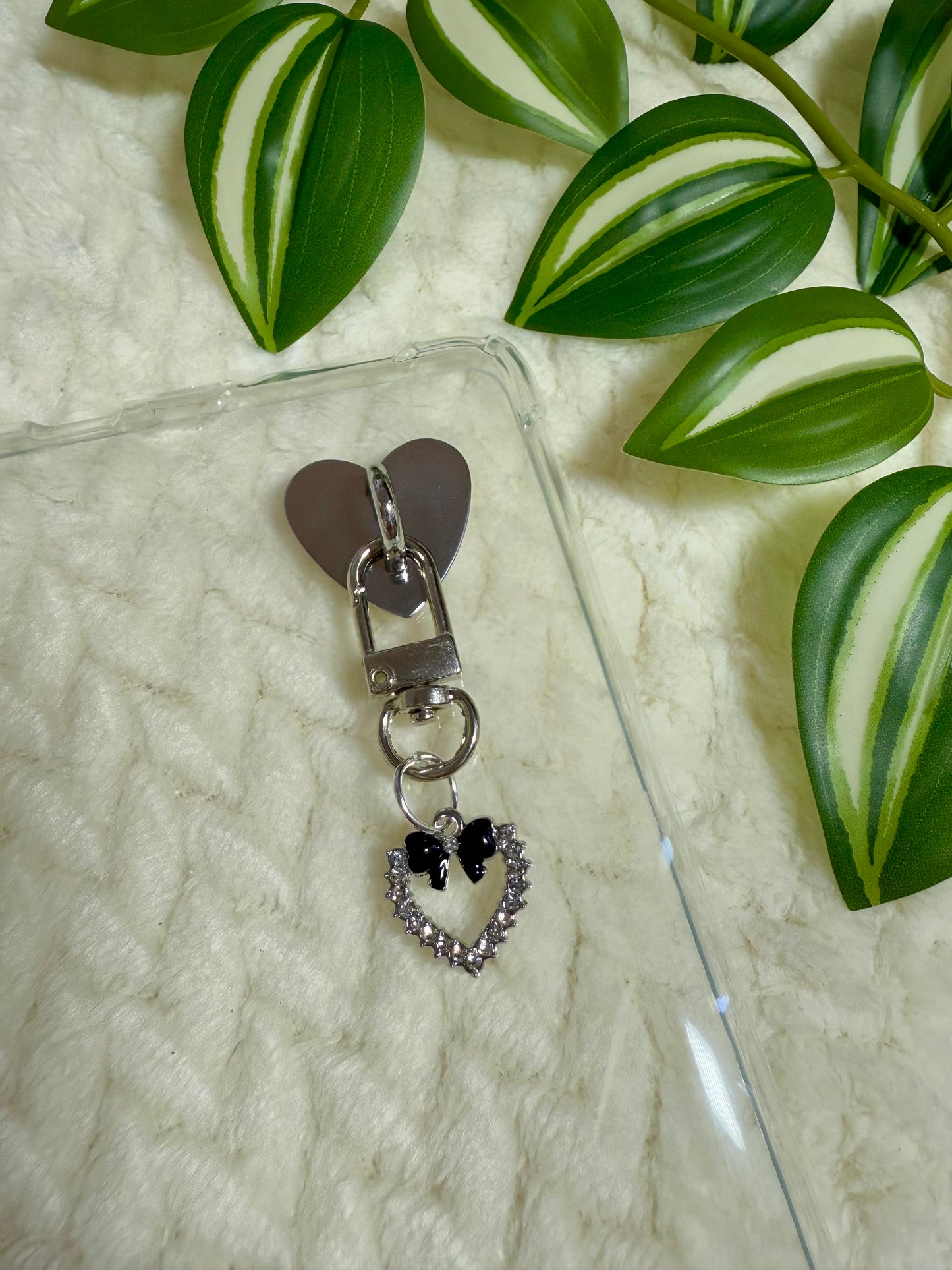 Heart-shaped charm with black bow on a clear kindle case.