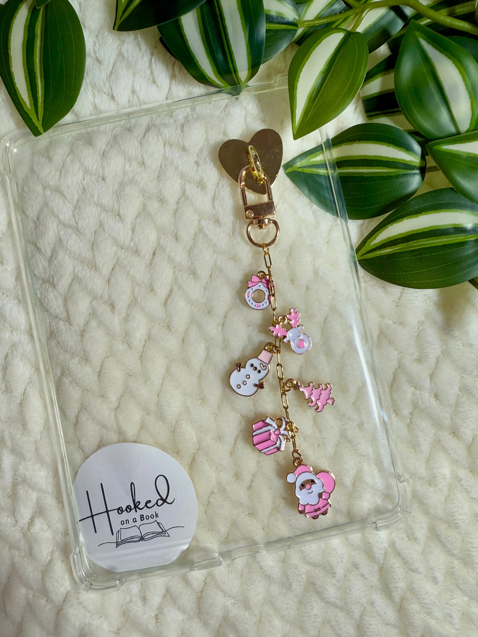 A chain of pink christmas charms attached to a clear kindle case