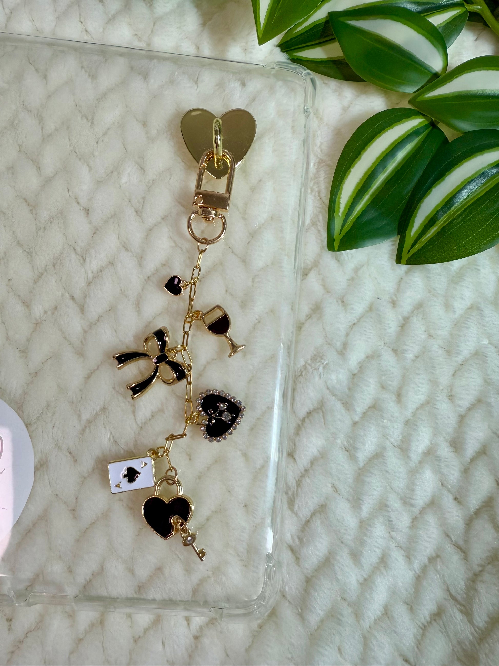A chain with heart charms and black heart key charm attached to a kindle device.