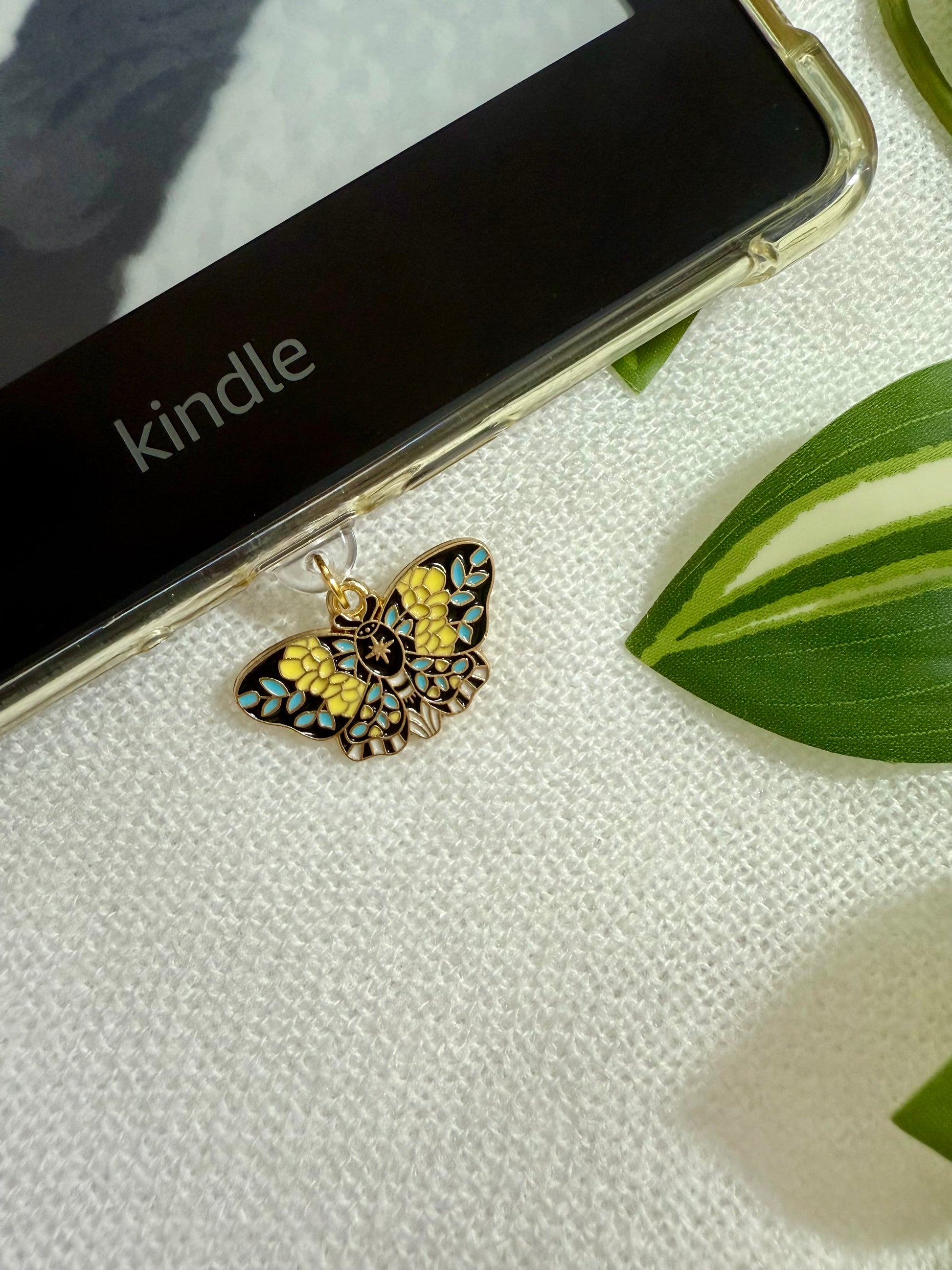 Butterfly-shaped charm on a Kindle device with a leaf in the background