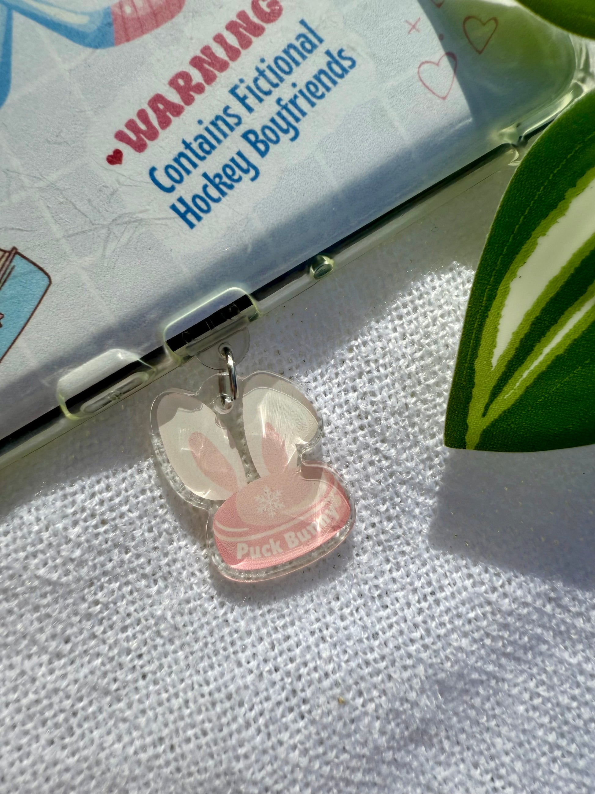 Pink bunny-shaped charm on a textured surface with a warning label in the background.